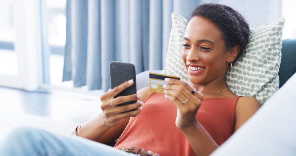 African American woman holding her phone and credit card to make a payment online